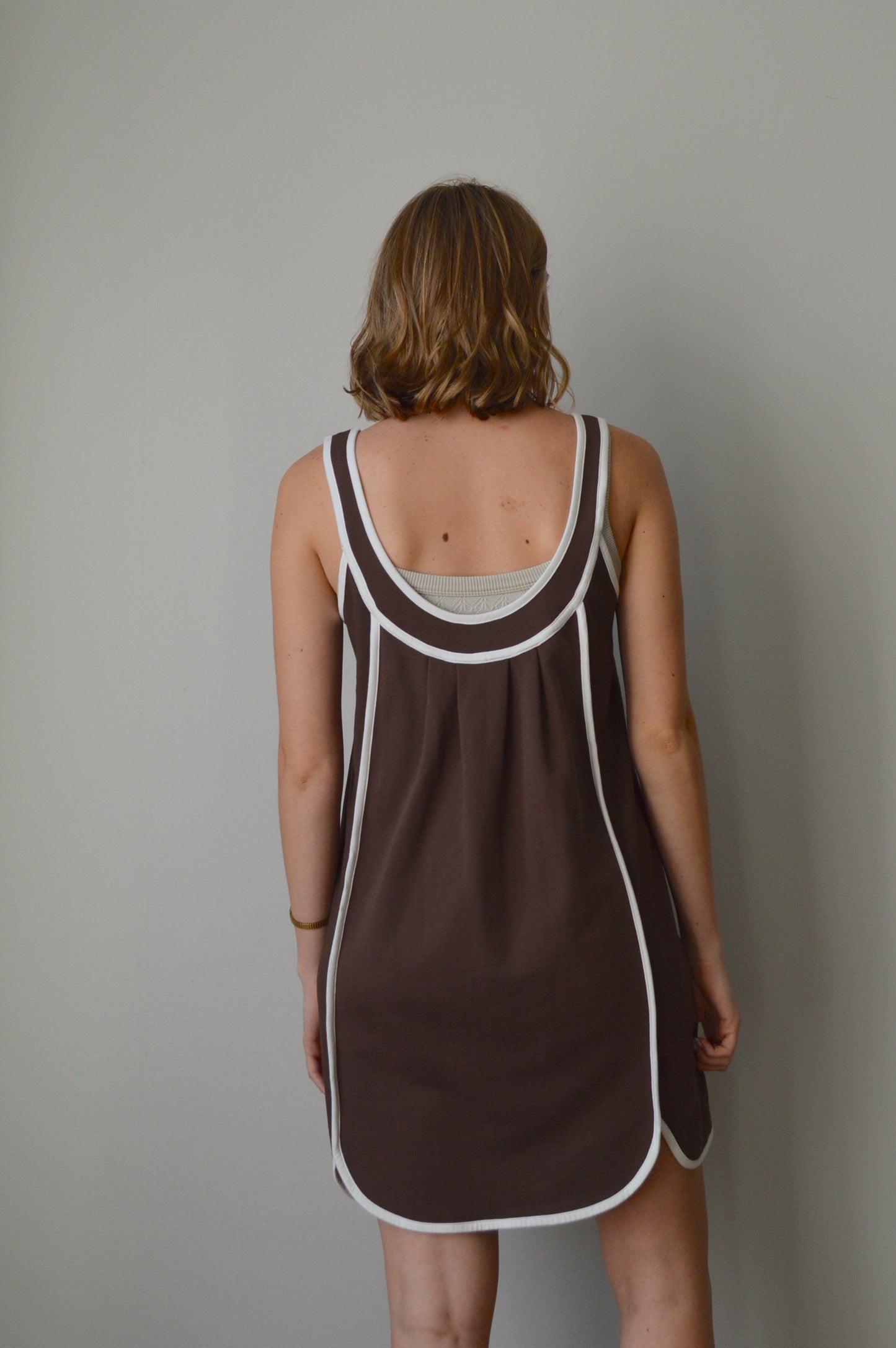 Brown dress with white trim worn by a person against a plain background