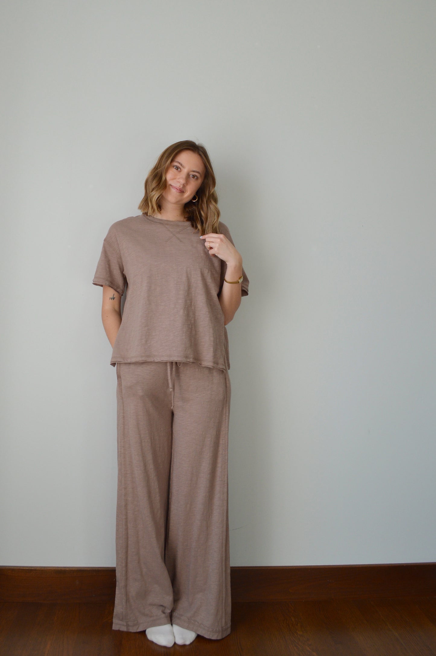 Woman wearing a brown outfit standing against a plain background
