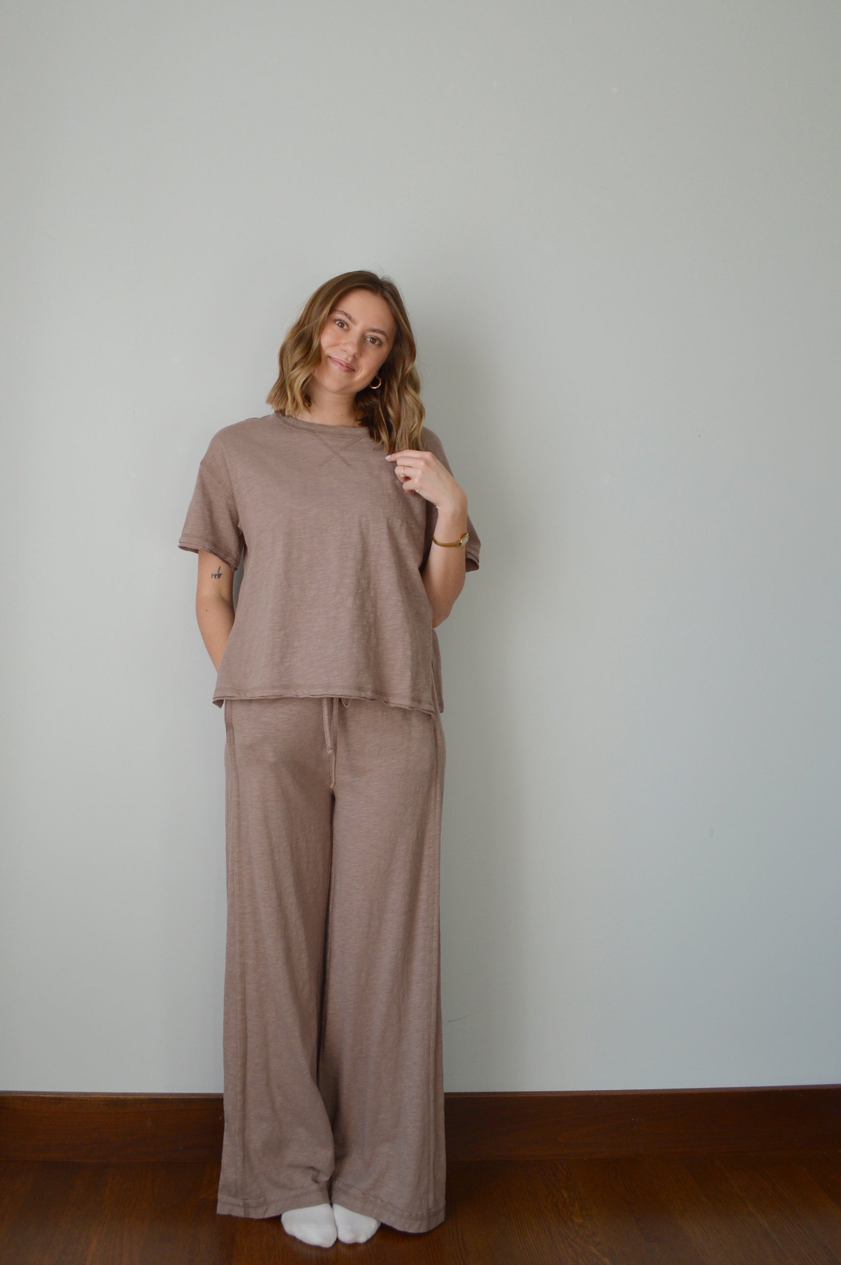 Woman wearing a brown outfit standing against a plain background