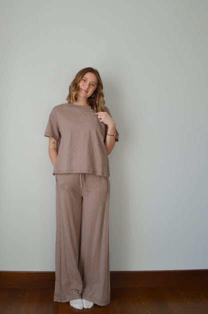 Woman wearing a brown outfit standing against a plain background