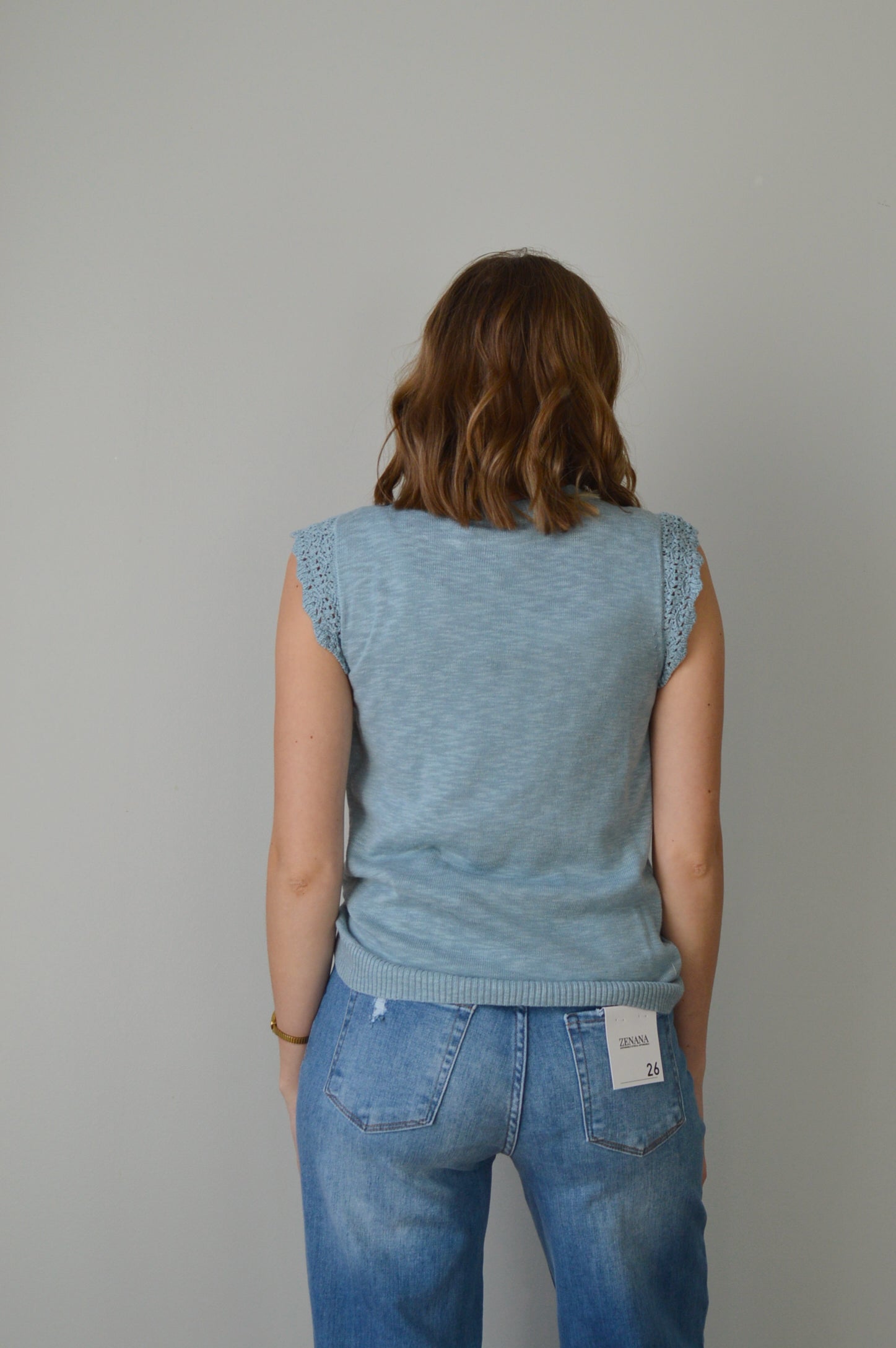 Woman wearing a light blue top and jeans on a plain background