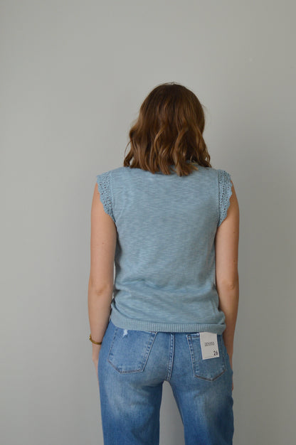 Woman wearing a light blue top and jeans on a plain background