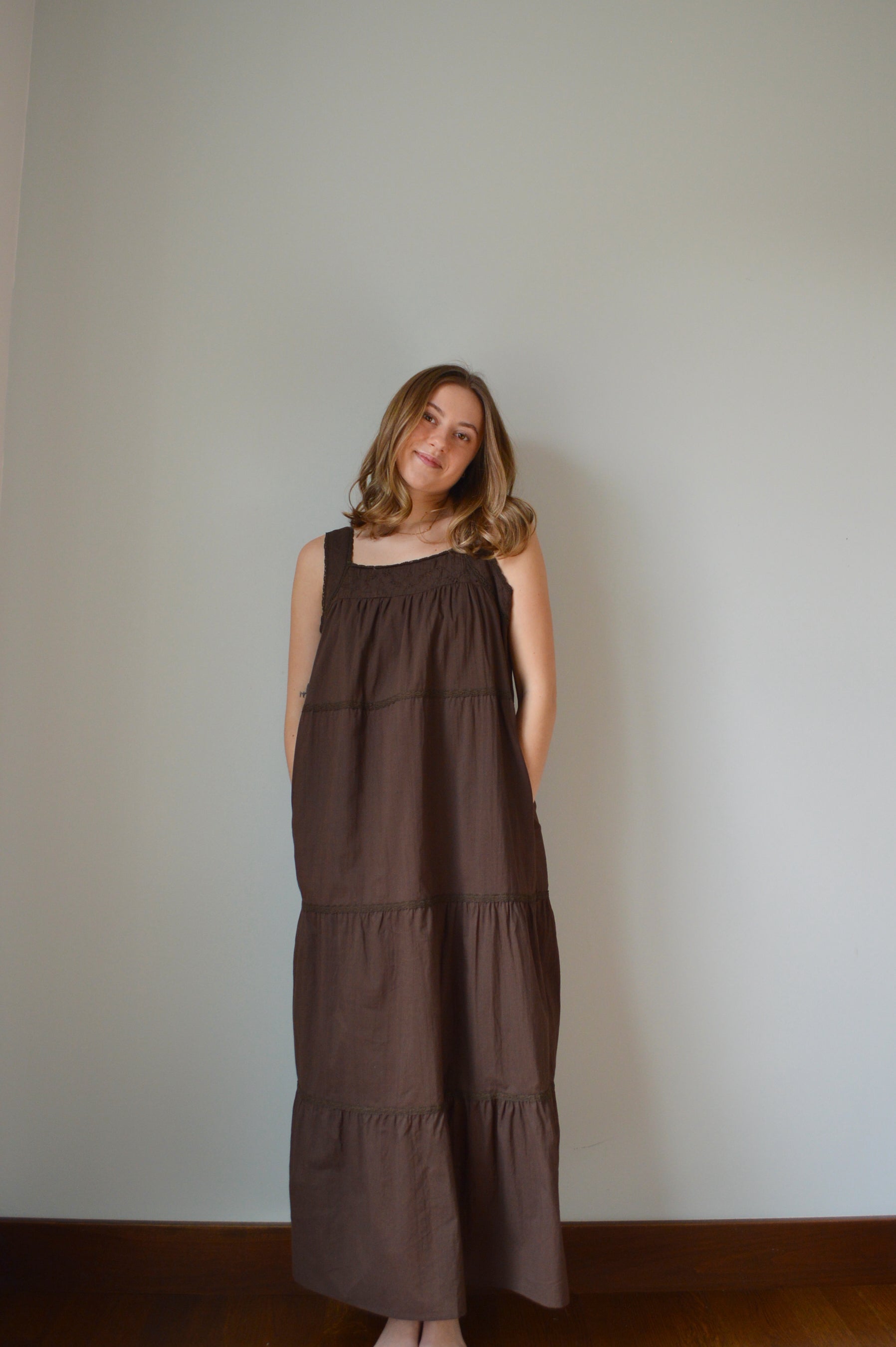 Woman wearing a brown dress standing against a plain background
