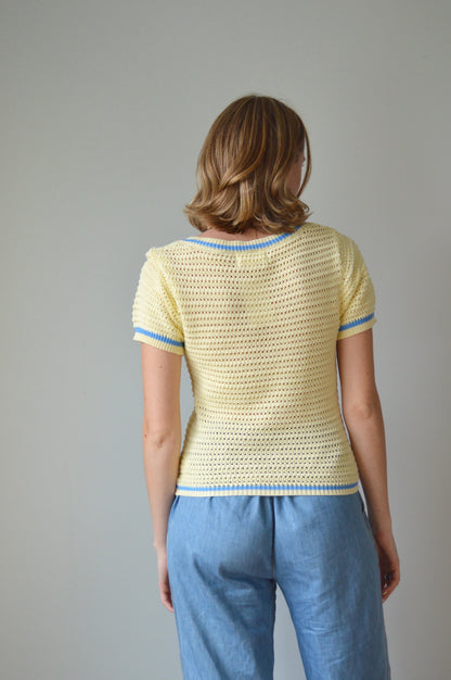 Woman wearing a yellow top and blue pants against a plain background