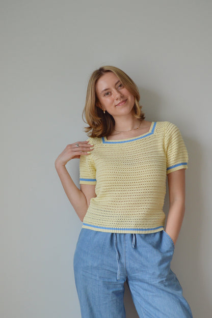 Woman wearing a yellow top and blue pants against a plain background