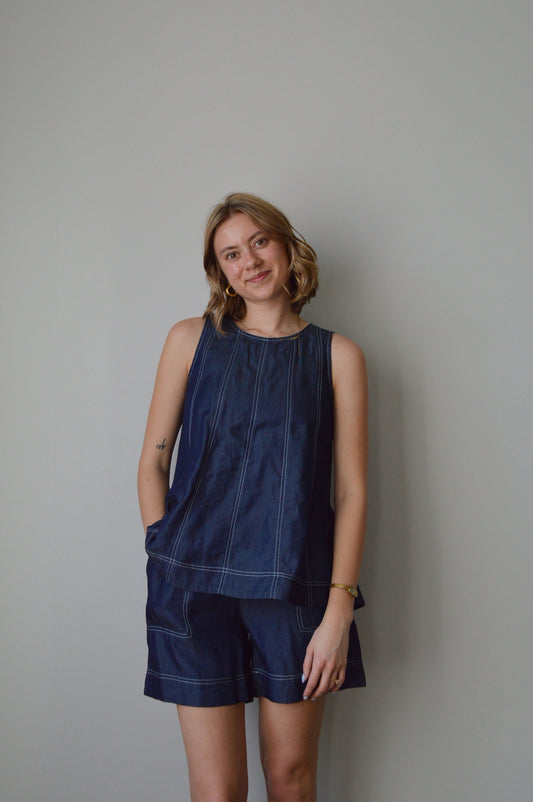 Woman wearing a blue top and shorts set against a plain background