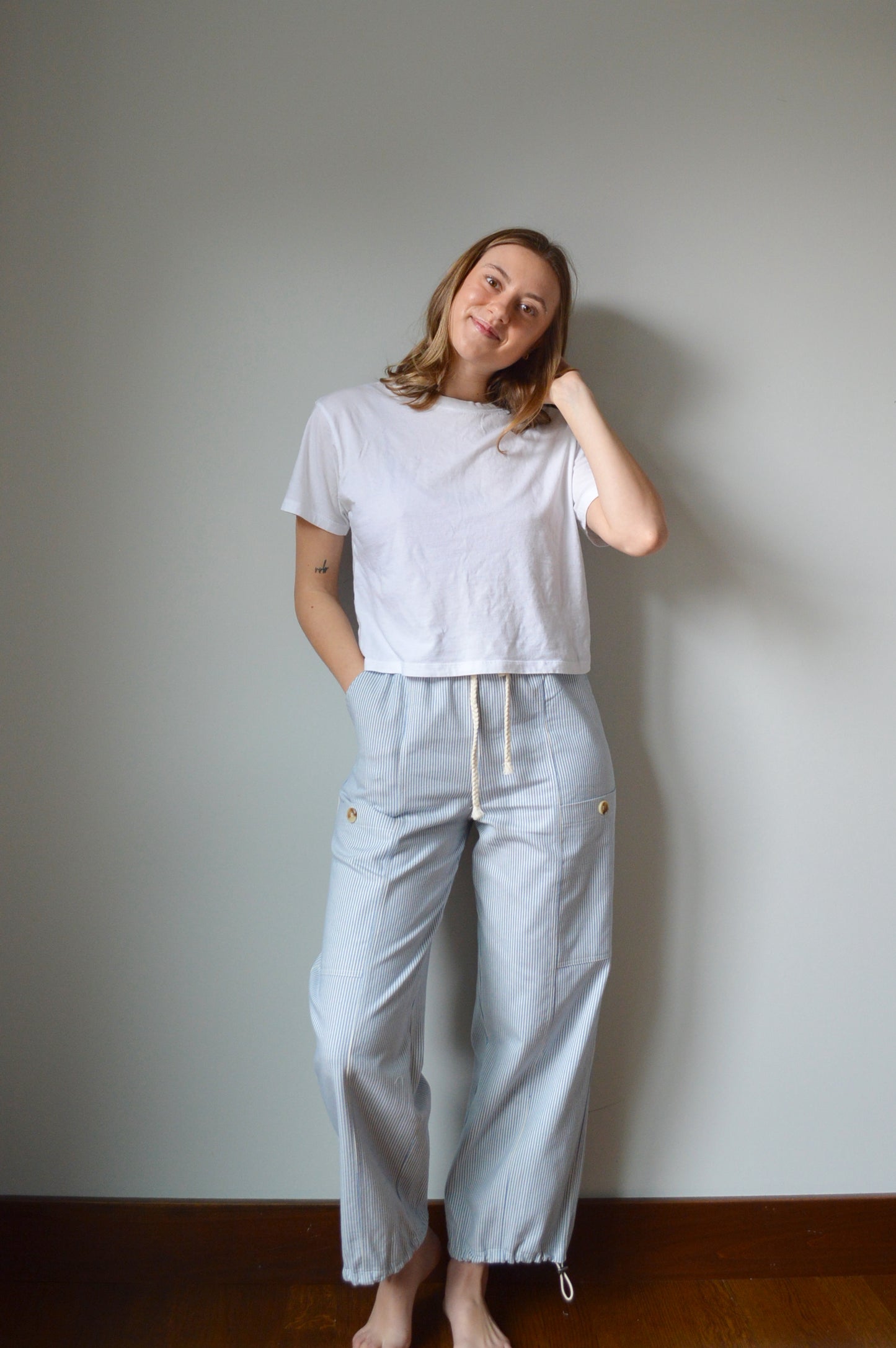 Woman wearing light blue and white striped pants against a gray wall