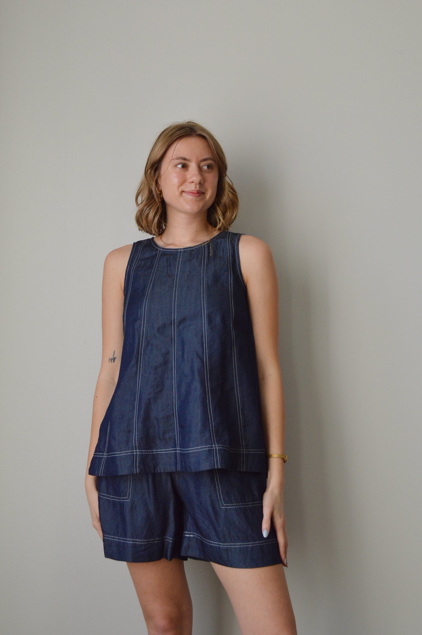 Woman wearing a blue top and shorts set against a plain background