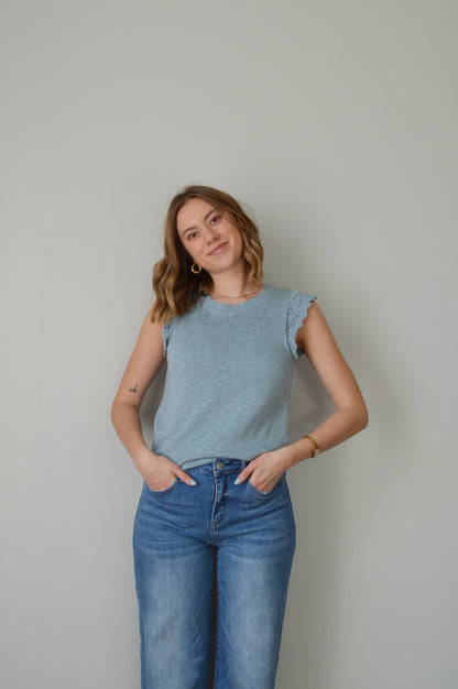 Woman wearing a light blue top and jeans on a plain background