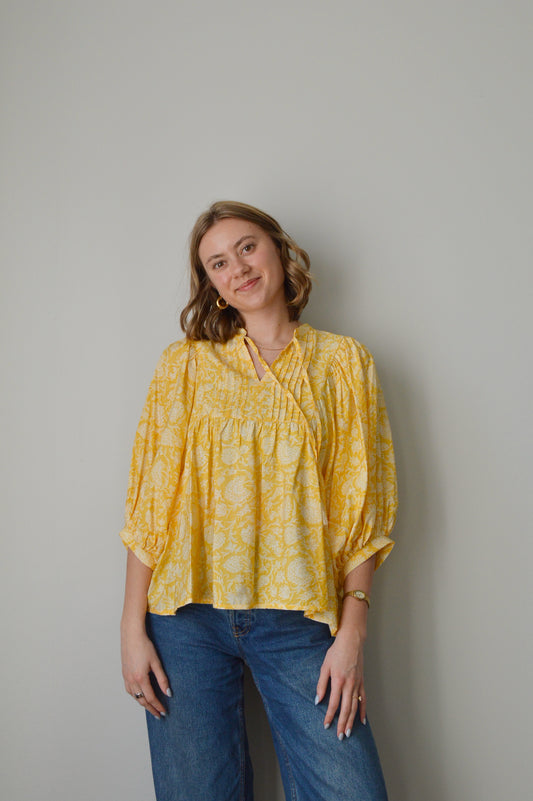 Woman wearing a yellow blouse and blue jeans 