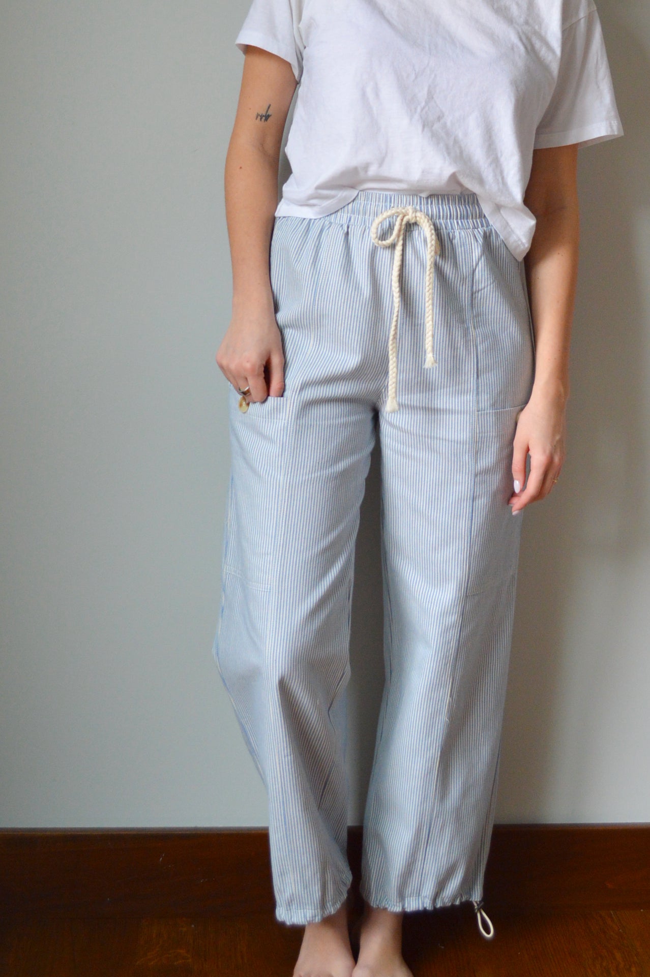 Woman wearing light blue and white striped pants against a gray wall