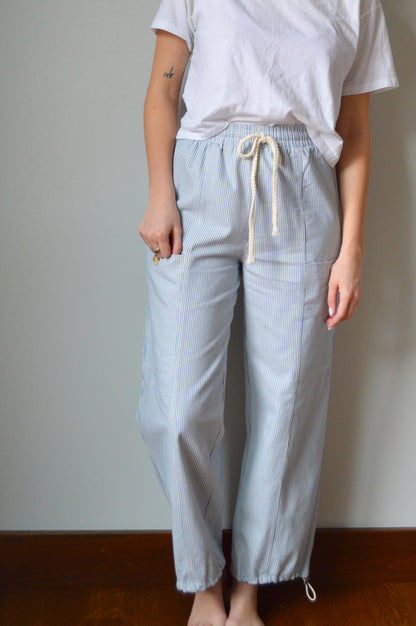 Woman wearing light blue and white striped pants against a gray wall