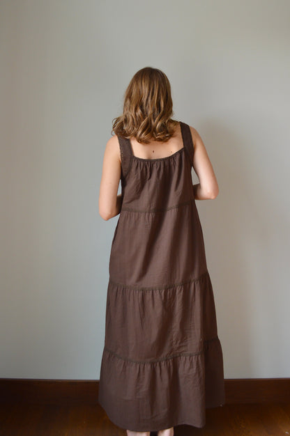Woman wearing a brown dress against a plain background