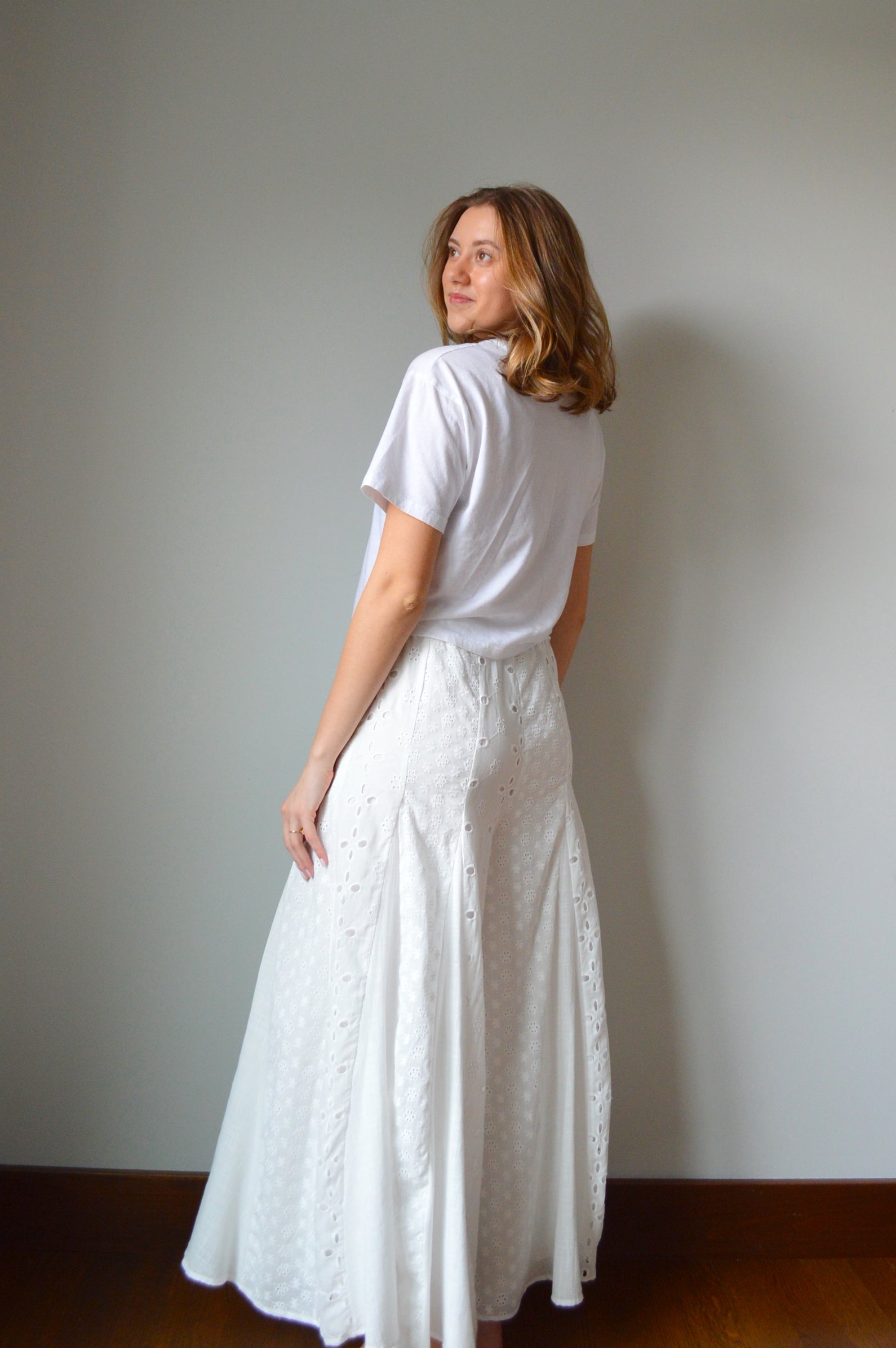 Woman wearing white eyelet wide leg pants standing against a plain background